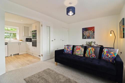a living room with a black couch and a kitchen at Round House view in Chesterfield