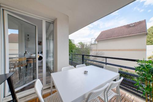 balcón con mesa blanca y sillas en Appartement cosy parking privé, en Saint-Ouen