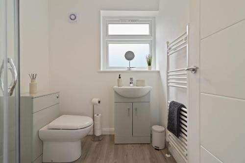 a bathroom with a toilet and a sink and a window at Round House view in Brimington