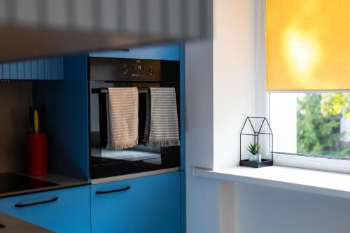 a kitchen with blue cabinets and a microwave at SongInn Lake Apartment in Zarasai