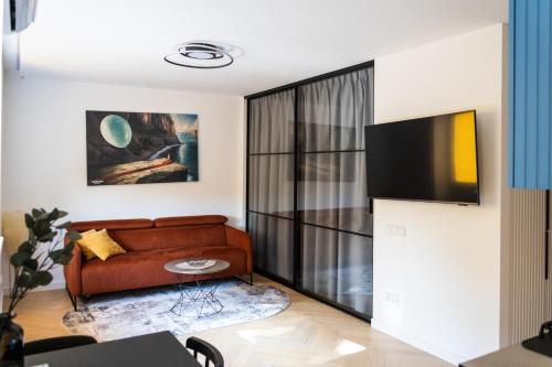 a living room with a couch and a tv at SongInn Lake Apartment in Zarasai