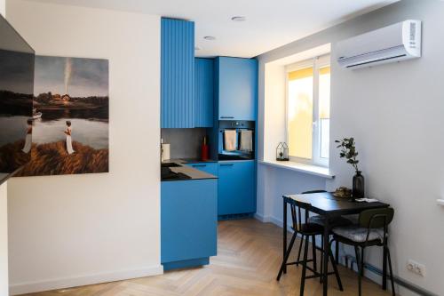 a kitchen with blue cabinets and a small table at SongInn Lake Apartment in Zarasai