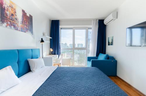 Un dormitorio con una cama azul y una silla azul. en Petrovdom Apartments 20-199a in RC Kvartet, Vasylya Lypkivskoho Street 16Г, en Kiev