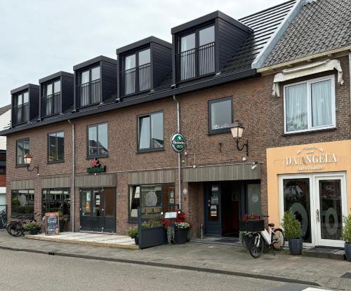 a large brick building with black windows on a street at Eetcafé Punt in Roelofarendsveen