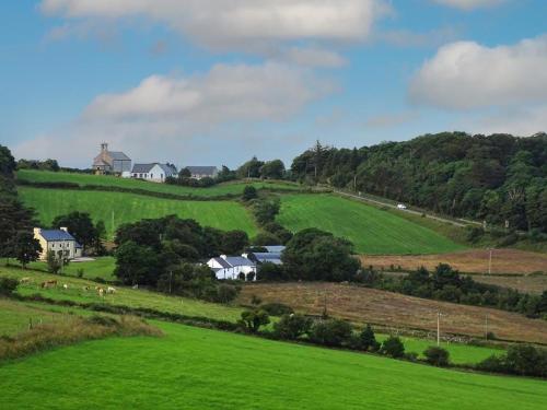 a green hillside with houses and sheep in a field at Church Bray View, Dunfanaghy in Dunfanaghy