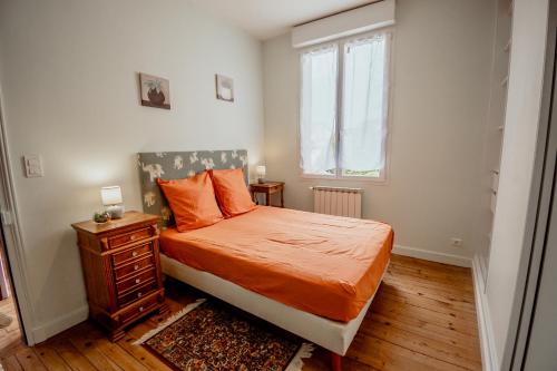 a bedroom with a bed with orange sheets and a window at Maison clim 3 ch Bord du Tarn Cours extérieure in Moissac