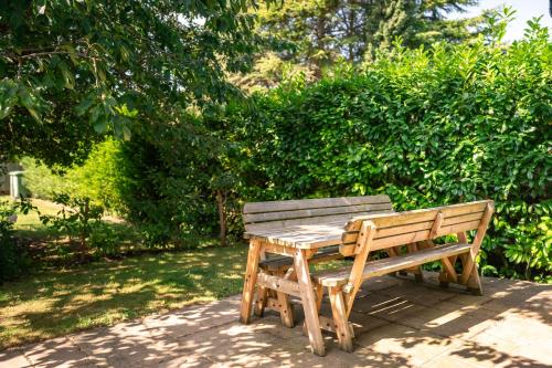 a wooden bench sitting in front of a bush at Garden Villa in Cambridge
