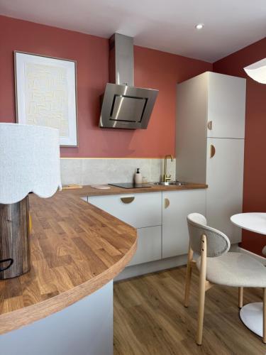 a kitchen with red walls and white cabinets and a table at Appartement Le rêve de Gaïa Climatisation et Wifi in Moulins