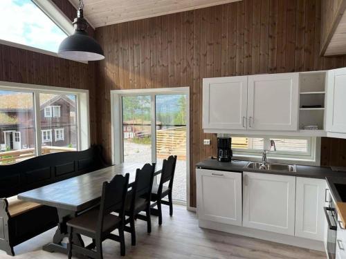 a kitchen with white cabinets and a table and chairs at New cabin Vrådal - sunny - fantastic hiking areas in Kviteseid
