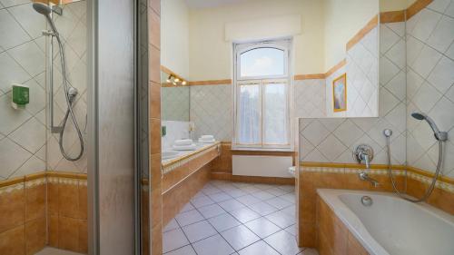 a bathroom with a tub and a shower and a sink at Landhotel Sophienhöhe in Kerpen
