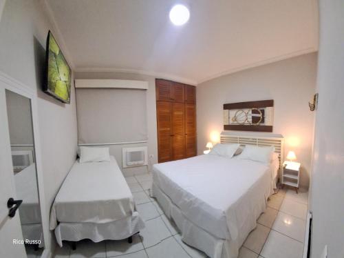 een kleine slaapkamer met twee bedden en een spiegel bij Riviera Flat 120 - Com serviços de hotelaria in Riviera de São Lourenço