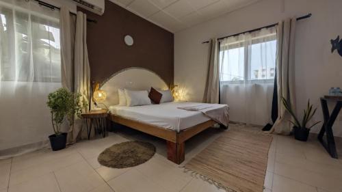 a bedroom with a bed and a large window at La Maison de Canelya in Cotonou