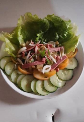 uma tigela branca cheia de salada com pepinos em Le Centurion em Brazavile