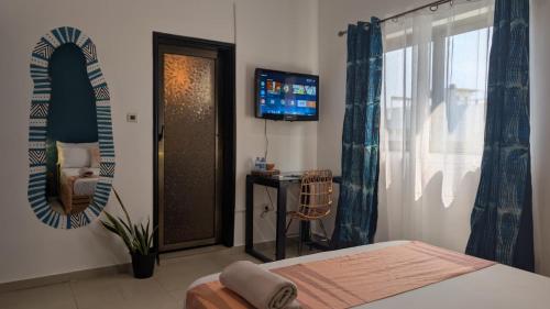 a bedroom with a bed and a mirror and a television at La Maison de Canelya in Cotonou