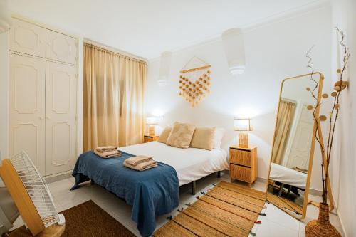 ein Schlafzimmer mit einem weißen Bett und einem Spiegel in der Unterkunft Stunning Apartment By Dreamplaces in Caliços