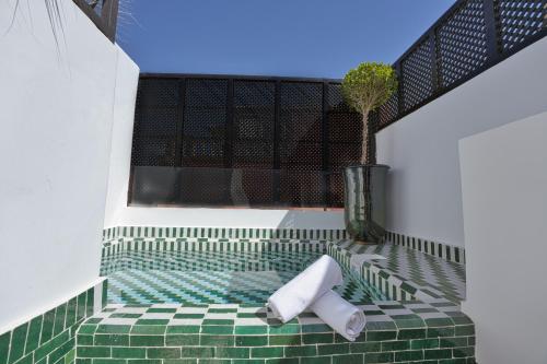 Una habitación verde y blanca con una planta y una ventana. en Dar Farah Riad luxe privé, 3ch, piscine chauffée, ptit déj, en Marrakech