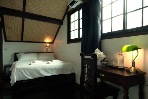 Un dormitorio con cama, escritorio y ventanas en Casa Acero, en Bangkok