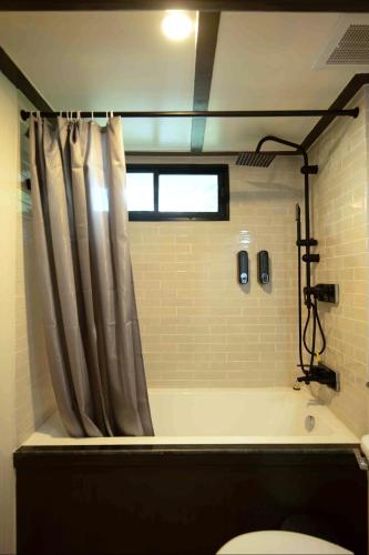 a bathroom with a bath tub with a shower curtain at Casa Acero in Bangkok