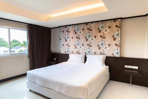 a bedroom with a white bed with a floral wall at Avana Bangkok Hotel & Convention Centre in Bangna
