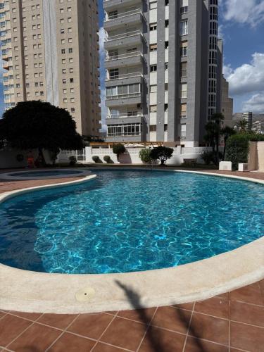 a large blue swimming pool with tall buildings in the background at Calpe apartamento LuXurY nuevo playa centrico parking wifi aire piscina patio in Calpe