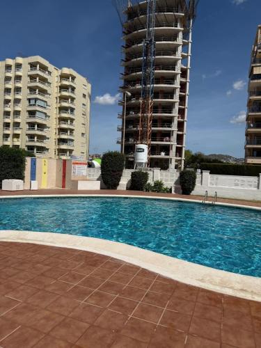 a swimming pool in front of two tall buildings at Calpe apartamento LuXurY nuevo playa centrico parking wifi aire piscina patio in Calpe
