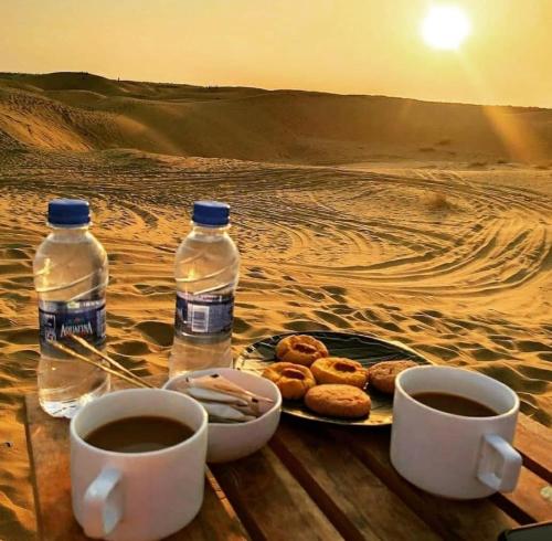 a table with two cups of coffee and a plate of donuts at Rajputana Desert Camp in Jaisalmer