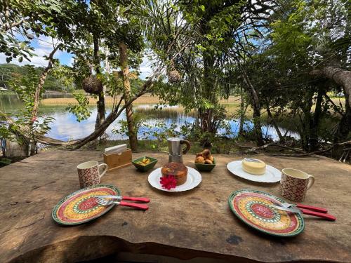 a table with plates of food and cups on it at The Private Forest Lake Tinys Aruanda in Mata de Sao Joao