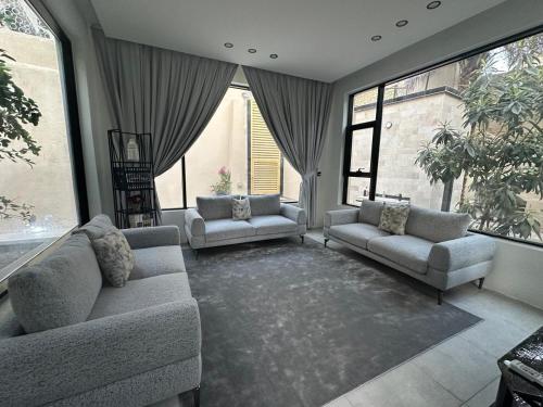 sala de estar con 2 sofás y ventanas grandes en عذوق, 