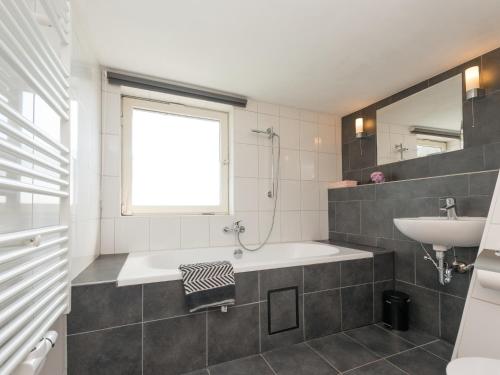 a bathroom with a tub and a sink and a window at Ferienhaus in Amelgatzen mit Terrasse in Emmerthal