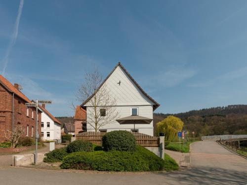 a white house with an umbrella on a street at Ferienhaus in Amelgatzen mit Terrasse in Emmerthal