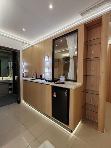 a kitchen with wooden cabinets and a black dishwasher at Suasana Suites Johor Bahru City Centre in Johor Bahru