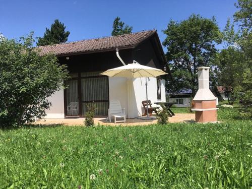 une petite maison avec une table et un parasol dans l'établissement Ferienhaus Wieselweg im Feriendorf Reichenbach 4, à Nesselwang