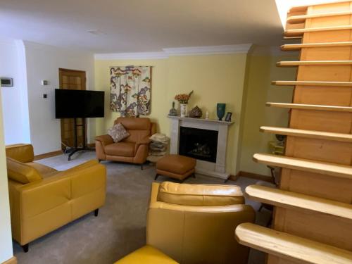 a living room with yellow furniture and a staircase at Oak Cottage - an inclusive peaceful haven in Newport