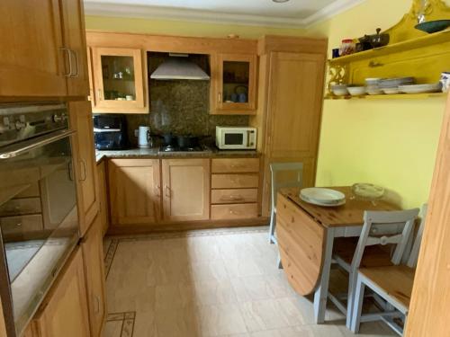a kitchen with wooden cabinets and a table and a microwave at Oak Cottage - an inclusive peaceful haven in Newport