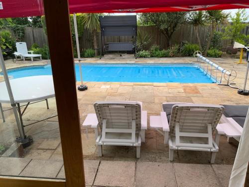 a swimming pool with chairs and a table and an umbrella at Oak Cottage - an inclusive peaceful haven in Newport