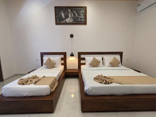 two beds sitting next to each other in a room at Eco Hotel Black & White - Anuradhapura in Mihintale