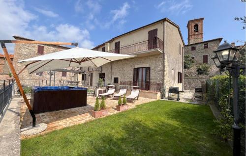 a patio with an umbrella and chairs in a yard at Lovely Apartment In Civitella Benazzone in Civitella Benazzone