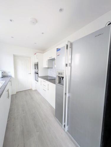 a kitchen with white cabinets and a stainless steel refrigerator at Chic En-suite Room with Office Garden and Parking New Renovation in Wainscot