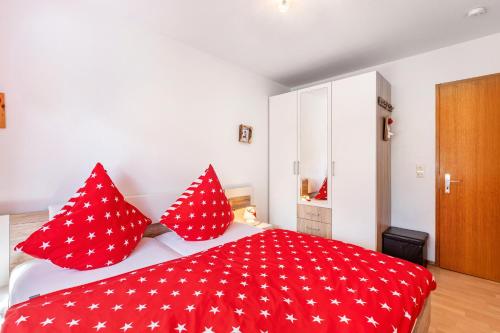 a bedroom with a red bed with red pillows at Ferienwohnung Schwarzwaldhirsch in Unterkirnach