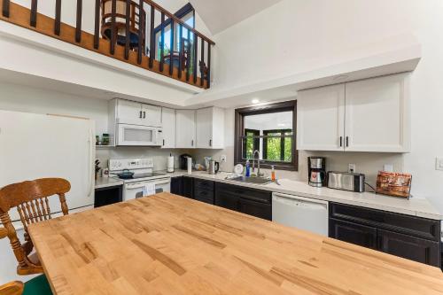a kitchen with white cabinets and a wooden table at Spacious Waterfront Mansion wHot tubPoolTable in East Stroudsburg
