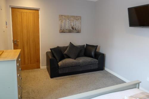 a black couch in a living room with a television at Pink House Skye in Portree