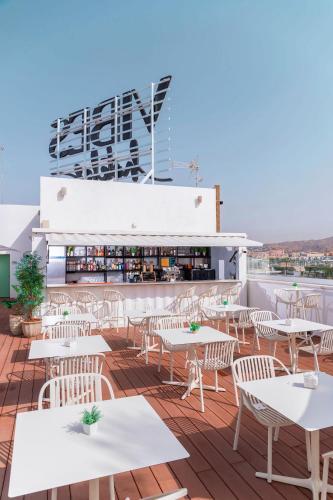 a patio with white tables and chairs on a roof at Hotel Málaga Vibes in Málaga