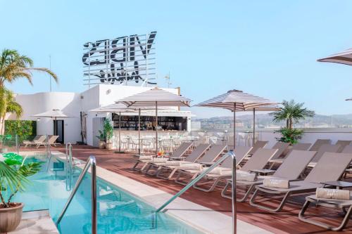 a pool with chairs and umbrellas on the roof of a hotel at Hotel Málaga Vibes in Málaga