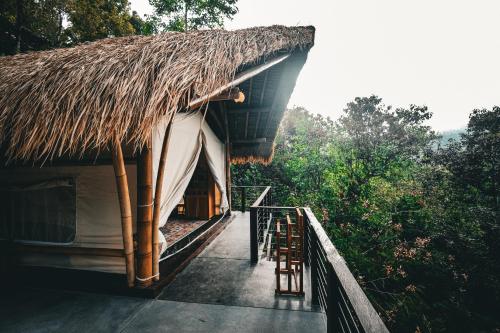 a hut with a thatched roof and chairs outside at Desa Eko in Munduk