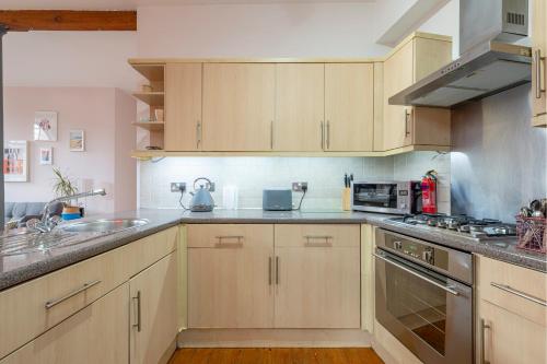 a kitchen with wooden cabinets and stainless steel appliances at 5 mins walk from centre, spacious city apt, open-plan in Nottingham