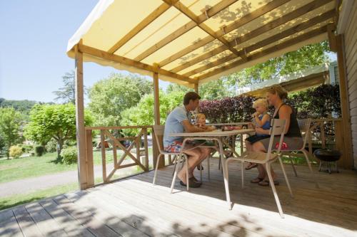 a family sitting at a table under a pergola at Camping RCN Belledonne in Le Bourg-dʼOisans