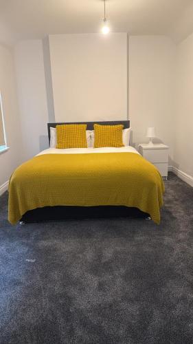 a bedroom with a bed with a yellow blanket at Lovely Room 3 in Avonmouth