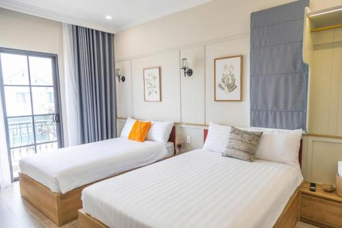 a hotel room with two beds and a window at JOYY Villa 4PN-3WC-5 giường NovaWorld Phan Thiết in Bình Tú