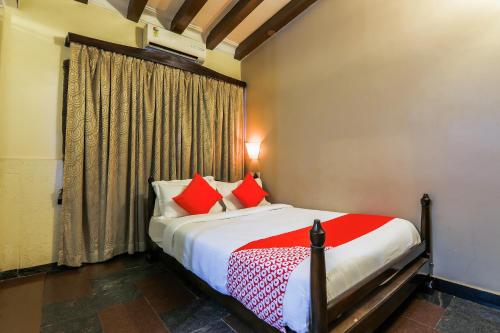 a bedroom with a bed with red pillows and a window at Hotel O Kams Coco De Parra in Goa