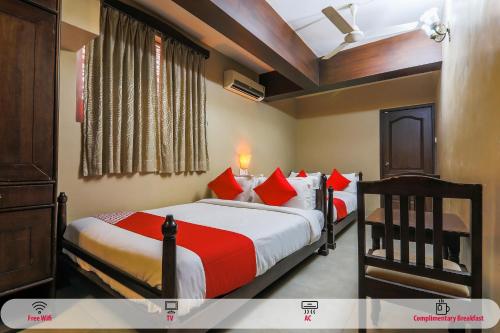 a bedroom with two beds with red and white pillows at Hotel O Kams Coco De Parra in Goa